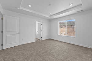 Unfurnished bedroom featuring a tray ceiling, light carpet, and recessed lighting