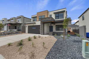 Contemporary house with stone siding, stucco siding, driveway, and a garage