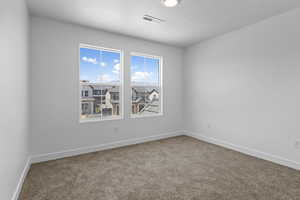 Carpeted spare room with baseboards and a textured ceiling