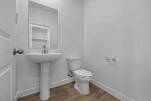Half bath with baseboards and wood finished floors