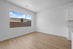 Unfurnished dining area featuring light wood-style floors, a textured ceiling, and recessed lighting