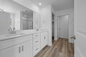 Full bathroom featuring a stall shower, double vanity, light wood-style floors, and recessed lighting