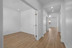 Hallway with light wood-type flooring and recessed lighting