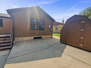 View of side of property with a patio and a storage shed