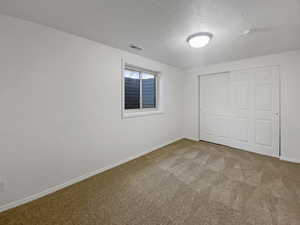 Unfurnished bedroom with carpet flooring, a textured ceiling, and a closet