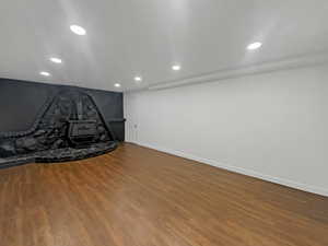 Below grade area featuring a wood stove, recessed lighting, and wood finished floors