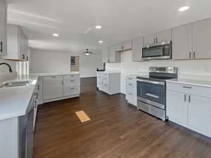 Kitchen featuring stainless steel appliances, dark wood finished floors, recessed lighting, light stone countertops, and ceiling fan