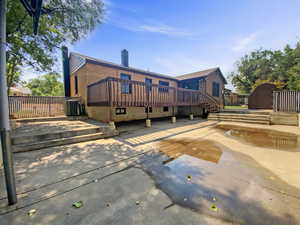 Back of property with a chimney, a shed, a deck, a patio area, and brick siding