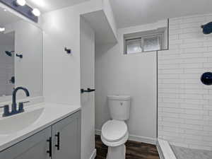 Bathroom featuring vanity, a tile shower, and dark wood-style floors