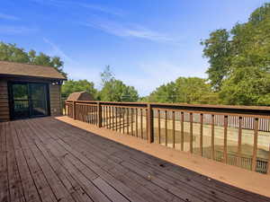 Deck with a storage unit and view of scattered trees
