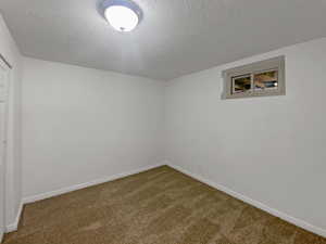 Carpeted spare room with baseboards and a textured ceiling