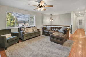 Living room with hardwood / wood-style floors, a chandelier, a ceiling fan, and recessed lighting