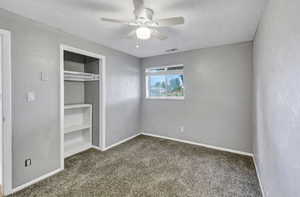 Unfurnished bedroom featuring carpet floors, a textured ceiling, a closet, a ceiling fan, and a textured wall