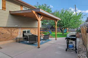 Fenced backyard with a trampoline, a patio area, a playground, grilling area, and an outdoor living space