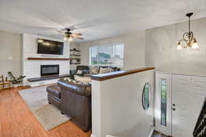 Living area featuring wood finished floors, a chandelier, and a fireplace