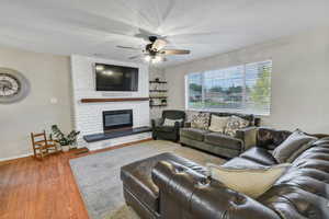 Living room featuring wood finished floors, a fireplace, and a ceiling fan