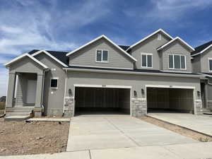 View of front of home featuring stone siding, driveway, and stucco siding