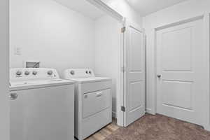 Laundry area featuring washing machine and dryer and dark carpet