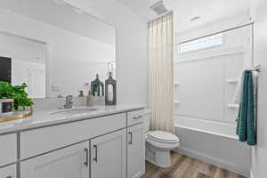 Bathroom with vanity, dark wood-style floors, and shower / bath combo with shower curtain