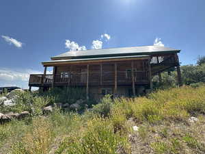 Rear view of house featuring a wooden deck, a metal roof, and faux log siding