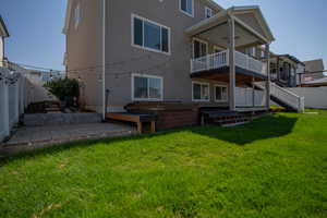 Back of property featuring a fenced backyard, a patio, stucco siding, a deck, and a hot tub