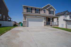 View of front of home with stone siding, concrete driveway, a porch, and stucco siding