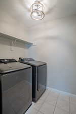 Washroom with light tile patterned floors and washing machine and dryer