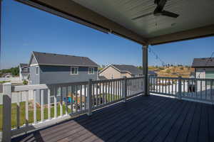 Wooden deck with a residential view, ceiling fan, and a lawn
