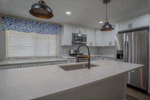 Kitchen with appliances with stainless steel finishes, white cabinetry, tasteful backsplash, hanging light fixtures, and recessed lighting