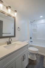 Bathroom with dark wood finished floors, vanity, tub / shower combination, and recessed lighting
