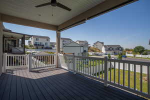 Wooden terrace featuring a ceiling fan, a residential view, and a yard