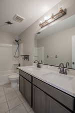 Full bath featuring shower / bathtub combination, light tile patterned flooring, double vanity, and a textured ceiling
