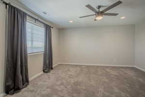 Empty room featuring light carpet, ceiling fan, and recessed lighting
