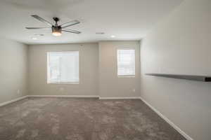 Unfurnished room featuring dark carpet and ceiling fan