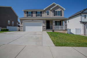 View of front of house featuring a porch, stucco siding, driveway, and stone siding