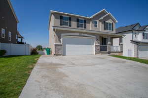 View of front of house with driveway, stone siding, and stucco siding