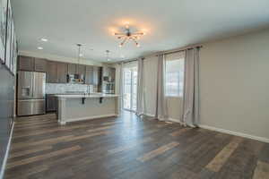 Kitchen with decorative backsplash, appliances with stainless steel finishes, a kitchen breakfast bar, decorative light fixtures, and a chandelier