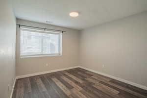 Spare room featuring dark wood-style floors and a textured ceiling