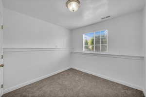 Carpeted spare room featuring baseboards