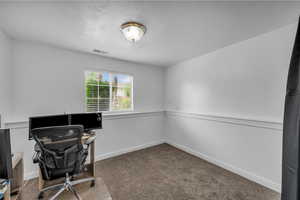 Office space with carpet floors and a textured ceiling