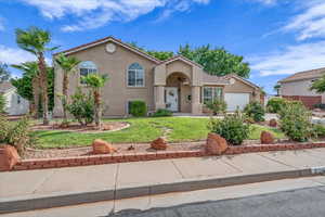 View of front of property featuring stucco siding, a front lawn, and an attached garage