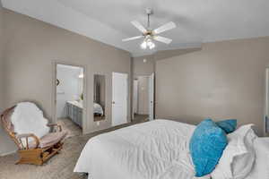 Carpeted bedroom with connected bathroom and ceiling fan