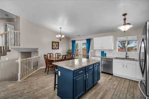 Kitchen featuring blue cabinetry, white cabinets, light stone countertops, decorative backsplash, and stainless steel appliances