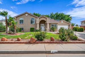 View of front of house featuring stucco siding, a front yard, a garage, and concrete driveway