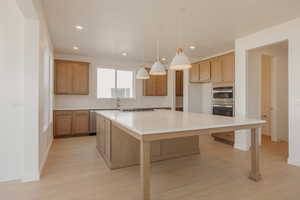 Kitchen featuring hanging light fixtures, a spacious island, light wood-type flooring, appliances with stainless steel finishes, and recessed lighting