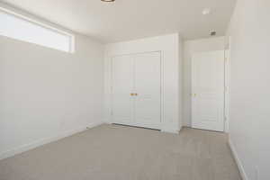 Unfurnished bedroom with light carpet, a textured ceiling, and a closet
