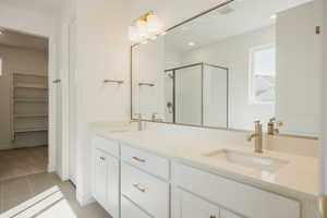 Full bath featuring a shower stall, double vanity, light tile patterned floors, recessed lighting, and a spacious closet