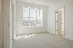Unfurnished bedroom featuring light carpet and baseboards