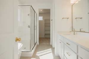 Full bathroom featuring a shower stall, vanity, light tile patterned floors, a spacious closet, and a soaking tub