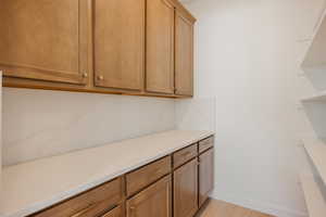 Kitchen with light stone countertops, light wood-style floors, brown cabinets, and backsplash